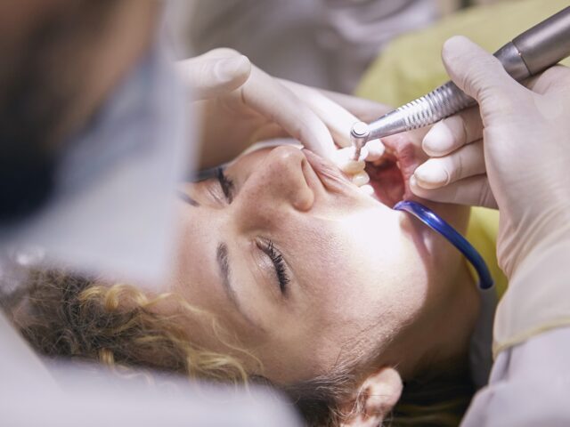 Woman's Teeth Being Clean By Dentist