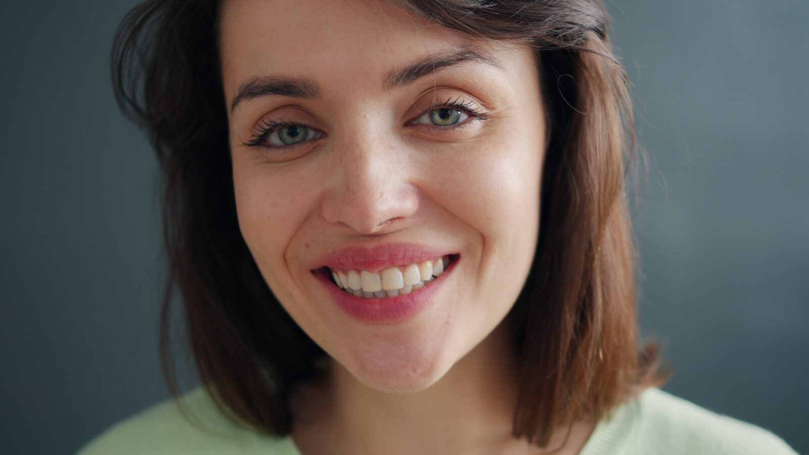 A woman with blue eyes smiles widely at the camera