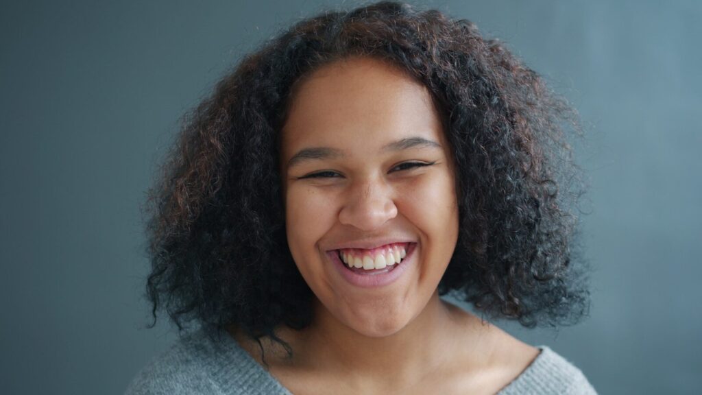 Young woman with curly hair laughing heartily